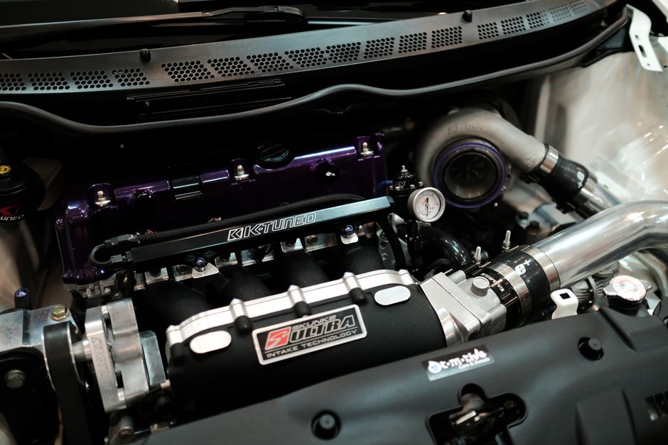 Detailed view of a customized car engine featuring a turbocharger and performance parts.